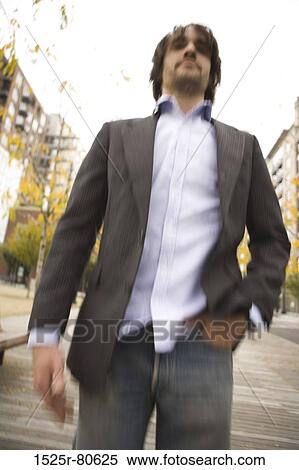 Stock Photography - Low angle view of a young man standing with his hand in his pocket. Fotosearch