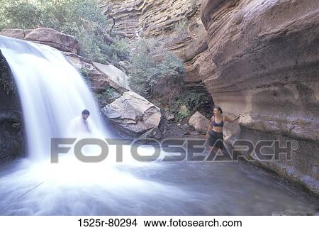 Man standing under a waterfall and a woman looking at him View Large Photo Image Picture - Man standing under a waterfall and a woman looking at him. Fotosearch