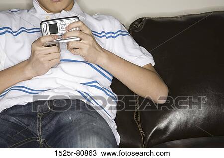 Stock Image - Mid section view of a man holding a mobile phone. Fotosearch