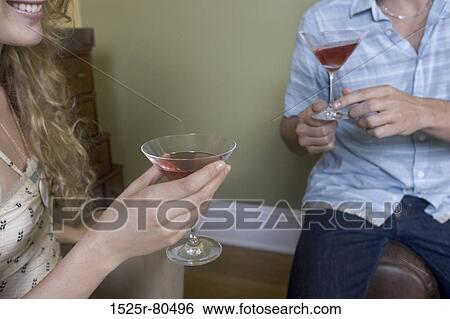 Mid section view of a young couple holding martini glasses View Large Photo Image Stock Photograph - Mid section view of a young couple holding martini glasses. Fotosearch