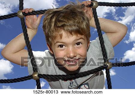 Portrait of a boy climbing up a net View Large Photo Image Stock Image - Portrait of a boy climbing up a net. Fotosearch