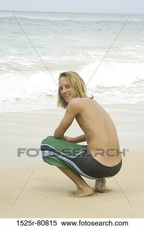 Portrait of a young man crouching on the beach and smiling View Large Photo Image Stock Photography - Portrait of a young man crouching on the beach and smiling. Fotosearch