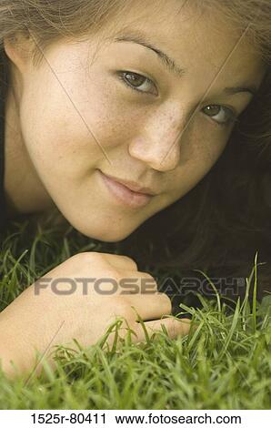 Portrait of a young woman lying on the grass View Large Photo Image Stock Image - Portrait of a young woman lying on the grass. Fotosearch