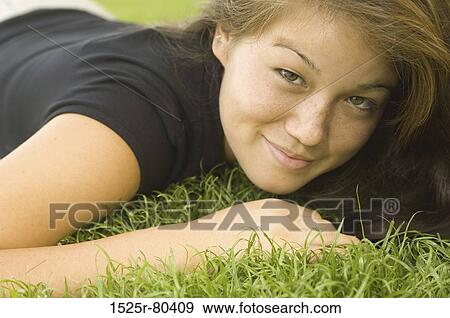 Portrait of a young woman lying on the grass View Large Photo Image Stock Photo - Portrait of a young woman lying on the grass. Fotosearch