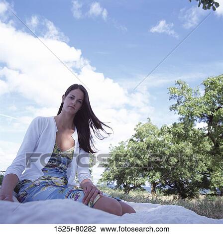 Stock Image - Portrait of a young woman sitting on a blanket. Fotosearch