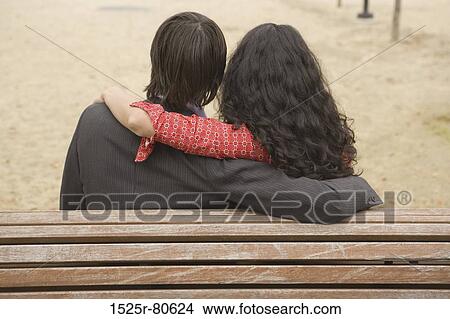 Rear view of a man and a woman sitting together on a bench View Large Photo Image Picture - Rear view of a man and a woman sitting together on a bench. Fotosearch
