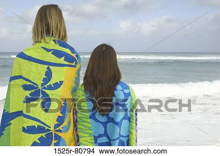 Rear view of a man and a woman standing on the beach View Large Photo Image Picture - Rear view of a man and a woman standing on the beach. Fotosearch