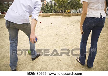 Rear view of a man throwing a ball with a woman standing beside him View Large Photo Image Stock Photograph - Rear view of a man throwing a ball with a woman standing beside him. Fotosearch