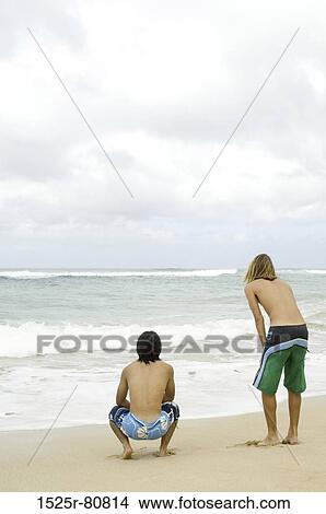 Rear view of two young men on the beach View Large Photo Image Picture - Rear view of two young men on the beach. Fotosearch