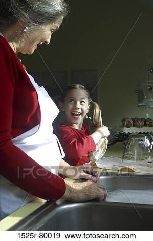 Side profile of a grandmother standing with her granddaughter in the kitchen View Large Photo Image Stock Photo - Side profile of a grandmother standing with her granddaughter in the kitchen. Fotosearch