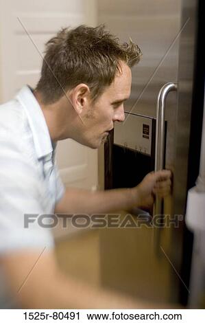 Side profile of a mid adult man opening a refrigerator door View Large Photo Image Stock Image - Side profile of a mid adult man opening a refrigerator door. Fotosearch