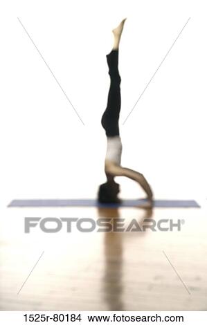 Picture - Side profile of a woman doing headstand. Fotosearch