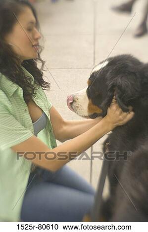 Stock Image - Side profile of a young woman holding a dog. Fotosearch