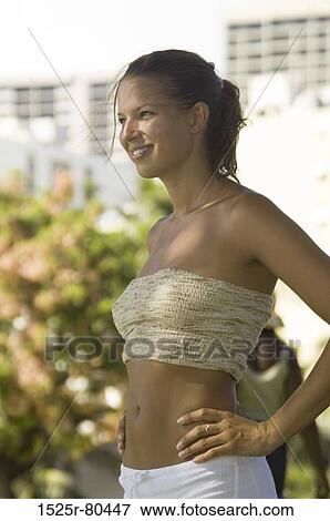 Side profile of a young woman standing with her arms akimbo View Large Photo Image Stock Photo - Side profile of a young woman standing with her arms akimbo. Fotosearch
