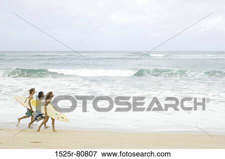 Side profile of a young woman with two young men walking on the beach View Large Photo Image Stock Photo - Side profile of a young woman with two young men walking on the beach. Fotosearch