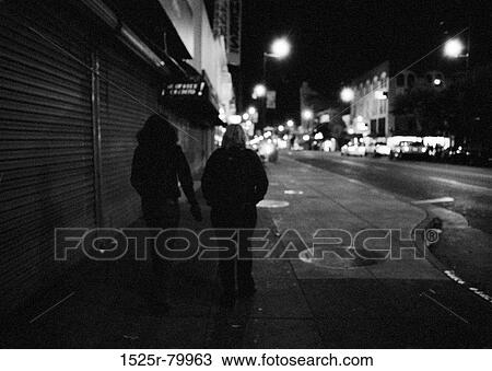 Silhouette of two people walking on a sidewalk View Large Photo Image Stock Image - Silhouette of two people walking on a sidewalk. Fotosearch