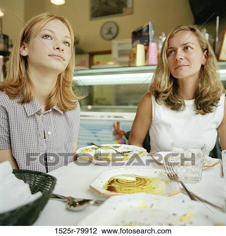 Two young women sitting in a restaurant View Large Photo Image Stock Image - Two young women sitting in a restaurant. Fotosearch