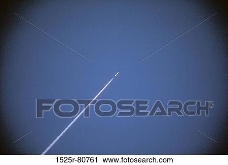 Stock Image - Vapor trail of a rocket against blue sky. Fotosearch