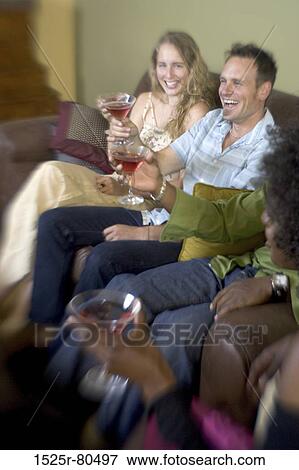Young couple sitting with their friends and holding martini glasses View Large Photo Image Stock Photo - Young couple sitting with their friends and holding martini glasses. Fotosearch