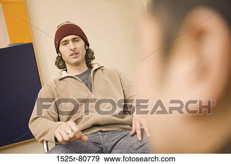 Young men sitting on a chair and talking View Large Photo Image Stock Photo - Young men sitting on a chair and talking. Fotosearch