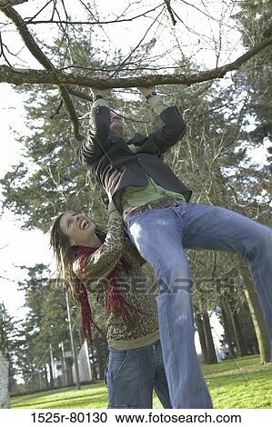 Young woman helping a young man reach out for a tree branch View Large Photo Image Stock Image - Young woman helping a young man reach out for a tree branch. Fotosearch