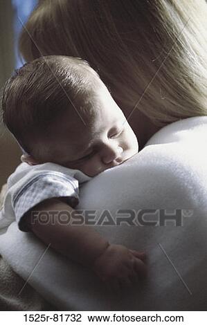 Stock Image - Baby boy asleep on his mother's shoulder. Fotosearch