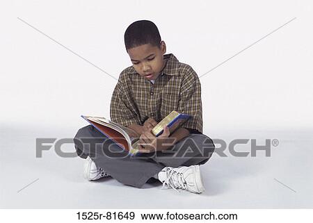 Boy sitting on the floor reading a book View Large Photo Image Stock Photo - Boy sitting on the floor reading a book. Fotosearch