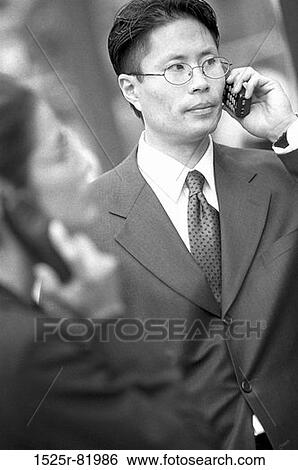 Stock Photograph - Businessman and a businesswoman talking on mobile phones. Fotosearch