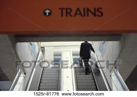 Businessman holding a briefcase on an escalator View Large Photo Image Stock Photograph - Businessman holding a briefcase on an escalator. Fotosearch