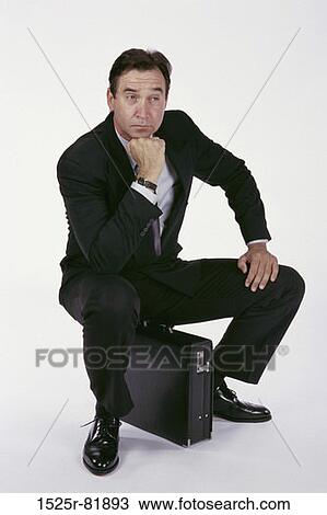 Businessman sitting on a briefcase View Large Photo Image Stock Image - Businessman sitting on a briefcase. Fotosearch