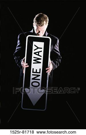 Businessman standing holding a street sign View Large Photo Image Stock Photo - Businessman standing holding a street sign. Fotosearch