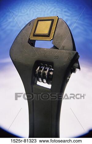 Stock Image - Close-up of a electronic chip between the jaws of a wrench. Fotosearch