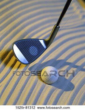 Stock Image - Close-up of a golf ball on the sand and a golf club. Fotosearch