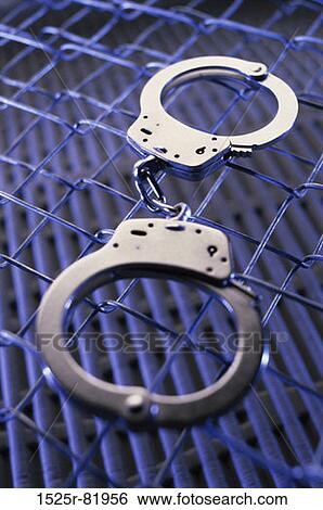 Close-up of a pair of handcuffs on a chain-link fence View Large Photo Image Stock Photograph - Close-up of a pair of handcuffs on a chain-link fence. Fotosearch
