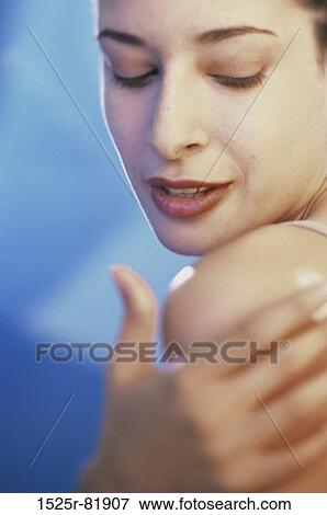 Close-up of a young woman applying moisturizer on her shoulder View Large Photo Image Stock Photo - Close-up of a young woman applying moisturizer on her shoulder. Fotosearch