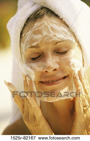 Close-up of a young woman applying lotion to her face View Large Photo Image Stock Photo - Close-up of a young woman applying lotion to her face. Fotosearch