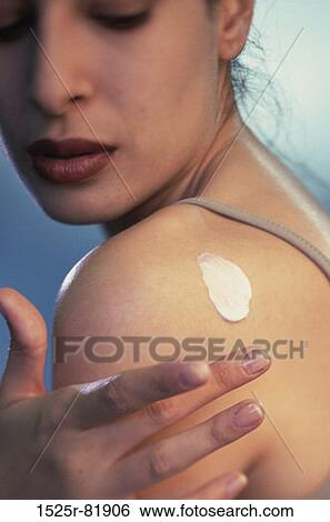 Close-up of a young woman applying moisturizer on her shoulder View Large Photo Image Stock Photograph - Close-up of a young woman applying moisturizer on her shoulder. Fotosearch