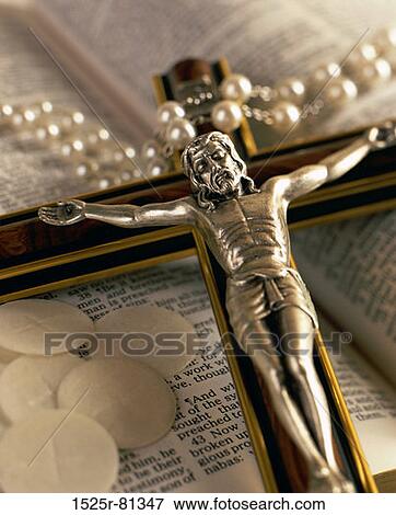 Stock Photo - Close-up of an opened bible with a rosary and crucifix lying on it. Fotosearch