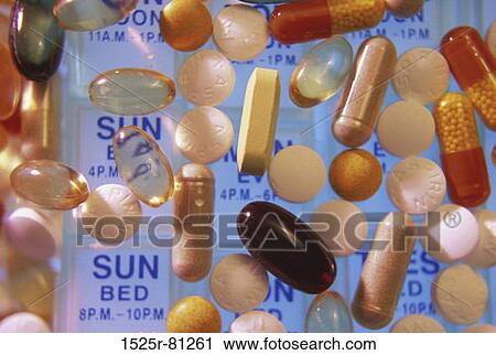 Stock Image - Close-up of assorted pills and capsules on a pill box. Fotosearch