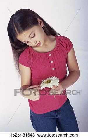 Stock Image - Girl looking down holding a flower. Fotosearch