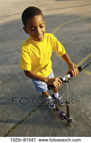 High angle view of a boy playing with a scooter View Large Photo Image Stock Photo - High angle view of a boy playing with a scooter. Fotosearch