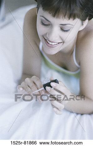 High angle view of a young woman applying nail polish View Large Photo Image Stock Photograph - High angle view of a young woman applying nail polish. Fotosearch
