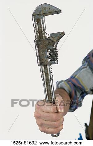 Stock Image - Human hand holding a pipe wrench. Fotosearch