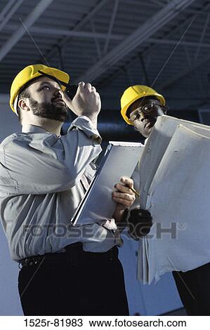Low angle view of two foreman holding blueprints View Large Photo Image Stock Image - Low angle view of two foreman holding blueprints. Fotosearch