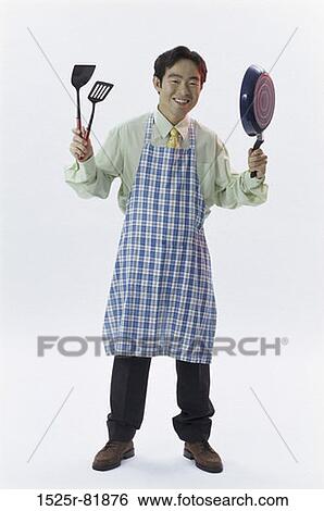 Man wearing an apron holding spatulas and a pan View Large Photo Image Stock Photograph - Man wearing an apron holding spatulas and a pan. Fotosearch