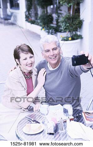 Mid adult couple taking a photograph of themselves View Large Photo Image Stock Image - Mid adult couple taking a photograph of themselves. Fotosearch