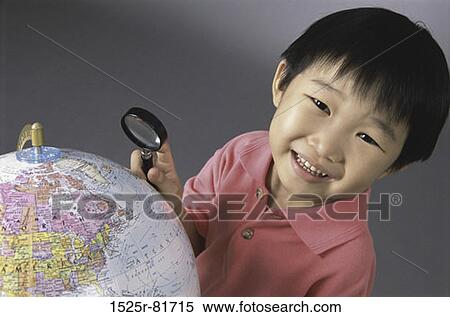 Stock Photography - Portrait of a boy holding a magnifying glass over a globe. Fotosearch