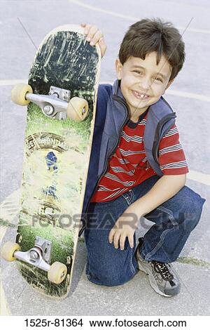 Portrait of a boy holding a skateboard View Large Photo Image Picture - Portrait of a boy holding a skateboard. Fotosearch