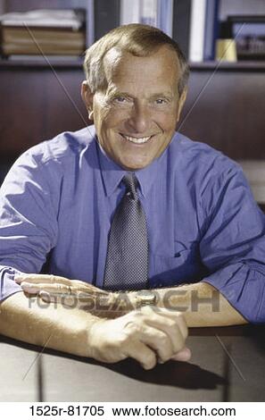 Portrait of a businessman seated behind an office desk smiling View Large Photo Image Stock Photography - Portrait of a businessman seated behind an office desk smiling. Fotosearch