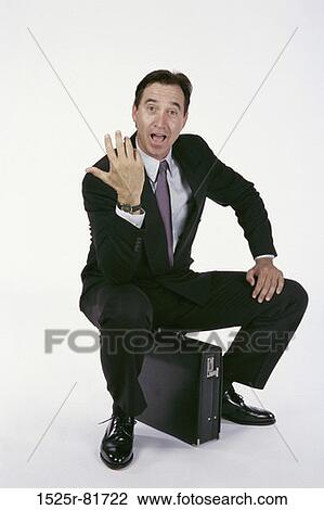 Portrait of a businessman sitting on a briefcase View Large Photo Image Stock Image - Portrait of a businessman sitting on a briefcase. Fotosearch